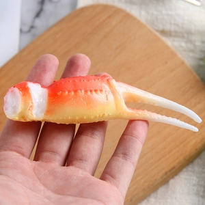 Handheld realistic crab claw model with textured orange to white gradient for food display