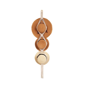 Handmade macrame hat organizer with boho tassels holding three straw hats on white background