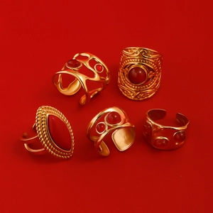 Flat lay of five vintage gold rings with red agate stones on a red background
