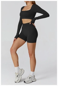 Side view of black seamless yoga set featuring long sleeve crop top and high waist shorts