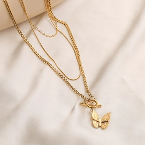 Gold layered chain necklace with butterfly pendant and OT buckle on soft fabric