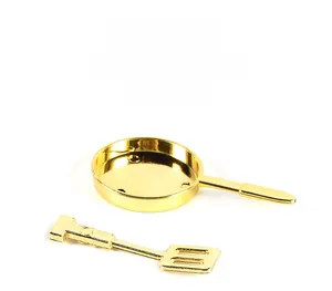 Detailed macro view of miniature golden alloy frying pan and spatula kitchen play set
