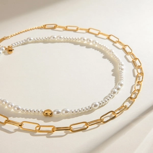Double-layered stainless steel necklace featuring a gold paperclip chain and heart pearl bead