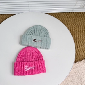 Detail of wool knit beanies in magenta and mint green with cursive Pensecole embroidery