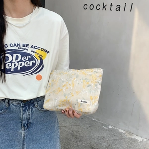 Close-up of beige floral embroidery makeup bag with delicate yellow and white flower patterns