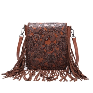 Close-up of bohemian brown embossed leather handbag featuring detailed floral carvings and fringe