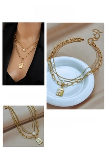 Detail view of layered gold chain necklace featuring pearl and portrait pendant
