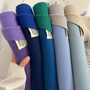 Detail of rolled solid color scarves in five shades showing soft cashmere-like texture