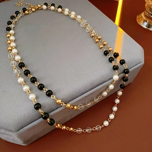 Détail d'un collier double rang en or et perles sur un coffret à bijoux en velours gris