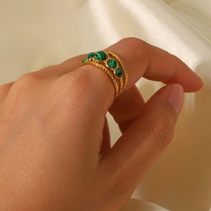 Detail of gold woven ring featuring multiple round malachite stones on a silk background