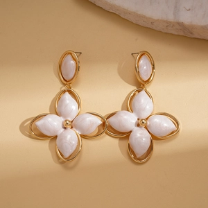 Detail of vintage gold clover drop earrings with pearly white inlay on beige background
