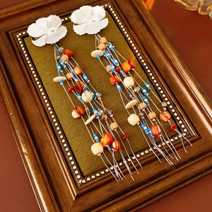 Detailed shot of bohemian floral earrings with shell tassels and wooden beads in a vintage frame