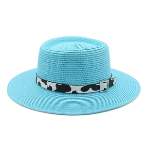 Detail of light blue straw boater hat with cow print ribbon and silver buckle decoration