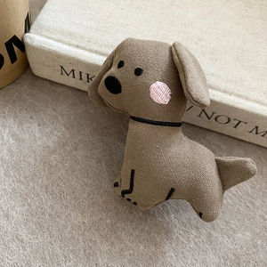 Close-up of brown plush puppy hair clip with detailed embroidery on cotton linen fabric