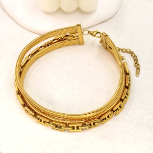 Macro detail of triple-layer gold necklace featuring H-link chain and 18K engraving