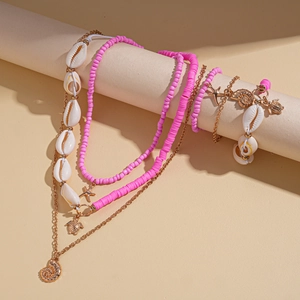Detail of seashell and starfish charms on a gold layered necklace with pink beads
