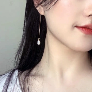 Detail of s925 silver long tassel earrings with white teardrop pearls worn by a model