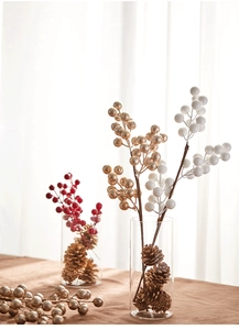 Festive Christmas berry branches in glass vase with natural pine cones decor