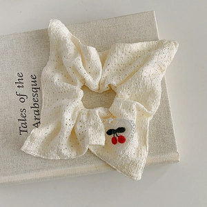 Gros plan d'un chouchou en dentelle blanche avec broderie cerise sur patch cœur