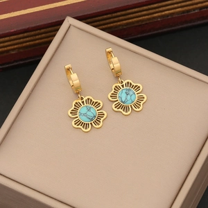Golden flower earrings with turquoise stone inlay on minimalist beige jewelry box display
