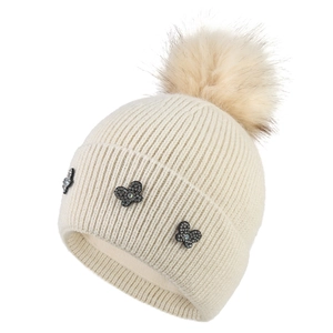 Off-white ribbed knit winter hat for women with plush pom-pom and rhinestone butterfly patches
