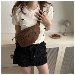 Detailed view of brown corduroy crossbody bag with strawberry pattern on model