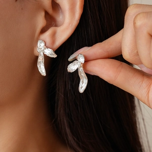 Minimalist silver pleated flower earrings with textured metallic finish on model