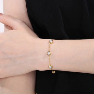 Vue détaillée d'un bracelet en perles dorées avec œil bleu porté sur le poignet