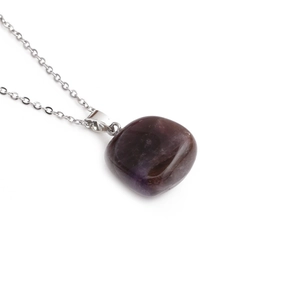 Detailed view of dark purple quartz pendant with silver metal chain on white background