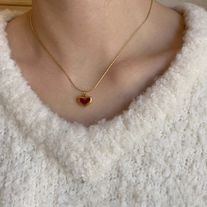 Elegant gold titanium steel necklace with a red heart pendant worn on a white sweater
