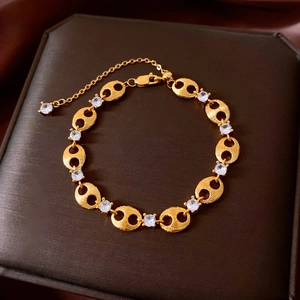 Detail of gold pig nose link bracelet with cubic zirconia and brushed metal finish