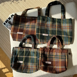 Detail of wool blend tote bags with vintage plaid patterns and soft woven handles