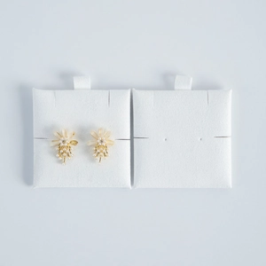 Macro view of floral drop earrings with white pearls and gold base on jewelry display pads