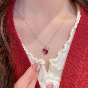 Detail of red gourd pendant necklace with gold chain worn by a model on neck