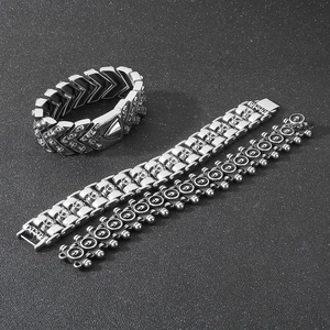 Detailed view of three punk-style stainless steel skull bracelets on a dark background