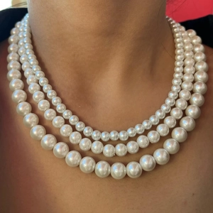 Elegant three-layer white shell pearl necklace featuring glossy round pearls on model