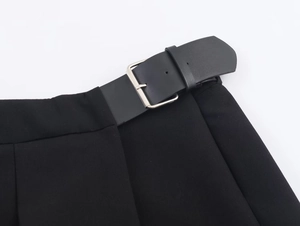 Gros plan d'une jupe-culotte noire plissée avec ceinture et boucle en métal argenté