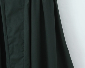 Detailed macro view of dark green smooth fabric with elegant drapes and folds