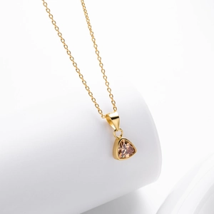 Detailed macro view of a champagne triangle pendant with a polished gold finish and chain