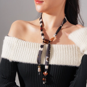 Detail view of ethnic style fabric scarf necklace with brown wooden beads on model