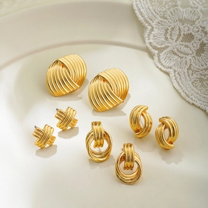 Set of four 14k gold geometric textured earrings displayed on a cream ceramic plate