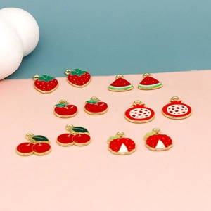Detailed view of enamel strawberry and cherry charms with golden loops for DIY jewelry
