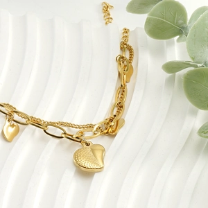 Detail of 18k gold heart charms on a double-layer stainless steel bracelet for women