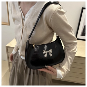 Detail view of glossy black patent leather bag with silver bow buckle decoration