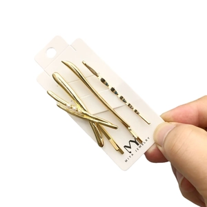 Golden 4-piece hair clip set with pearls and wave designs on card, held by hand