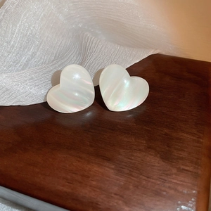 Macro shot of heart-shaped mermaid resin earrings with iridescent luster on wood surface