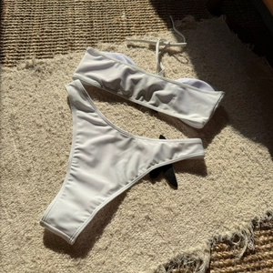Detailed top view of a white two-piece bikini with starfish embroidery on flat lay carpet
