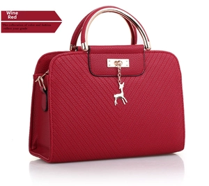 Detail of wine red handbag featuring V-shape quilting and golden deer pendant