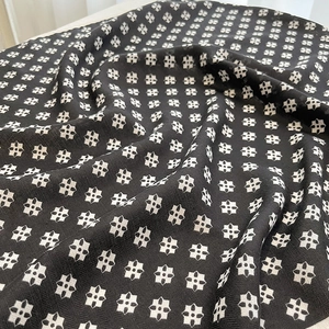 Detailed macro view of black herringbone fabric featuring a white floral geometric print
