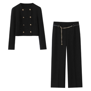 Dettaglio blazer corto doppiopetto nero e pantaloni larghi con cintura a catena oro